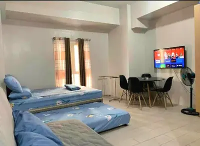 a room with two beds and a table and a tv at Eighty One Newport Blvd Condo near NAIA3 in Manila