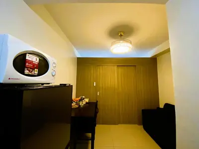 a room with a television and a table and a ceiling at Ameera Condo Stay in Manila