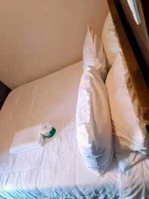 a bed with a white pillow and a bottle on it at Budget-Friendly Condo in Makati in Manila