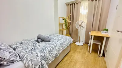 a bedroom with a bed and a desk and a fan at Brand New Cozy 2 BR unit in Pasig in Manila