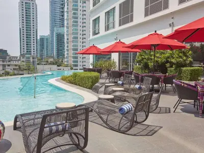 a group of tables and chairs with umbrellas next to a pool at Premium Twin Suite at Novotel Acqua - City View in Manila
