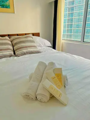 a bed with two folded towels and two boxes on it at Luxury 2BR with Stunning Skyline Views in BGC in Manila