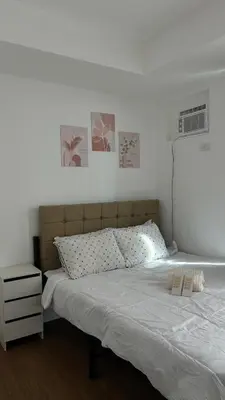 a bedroom with a large bed with white sheets and posters at Condo Unit in Parañaque by Casa Esplanade in Manila