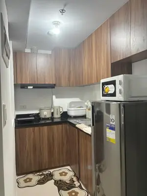 a small kitchen with a refrigerator and a microwave at Condo Unit in Parañaque by Casa Esplanade in Manila