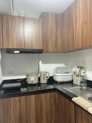 a kitchen with wooden cabinets and a counter top at Condo Unit in Parañaque by Casa Esplanade in Manila