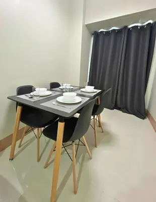 a dining room table with chairs and a black curtain at Shore 3 Residences in Manila