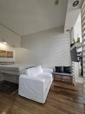 a living room with a bed and a white couch at Cozy Hotel-Style Studio Unit for Rent at Eastbay Residences by Rockwell in Manila