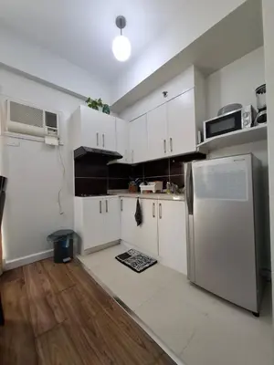 a kitchen with white cabinets and a refrigerator at Cozy Hotel-Style Studio Unit for Rent at Eastbay Residences by Rockwell in Manila