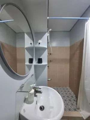 a bathroom with a sink and a mirror and a shower at Cozy Hotel-Style Studio Unit for Rent at Eastbay Residences by Rockwell in Manila