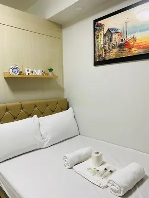 a bedroom with a white bed with a picture on the wall at Sea Residences in Manila