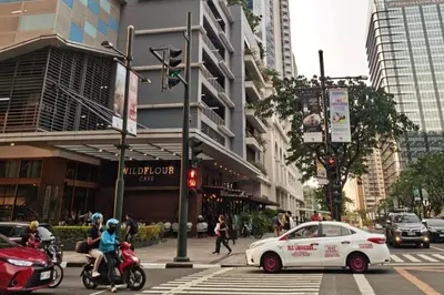 a white car on a busy city street with buildings at Uptown Parksuites - Elegant 2 Bedroom Unit with Balcony in BGC in Manila
