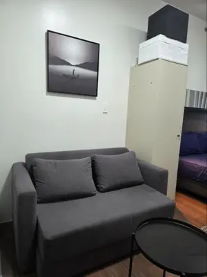 a living room with a couch and a tv on the wall at Air Residences in Manila
