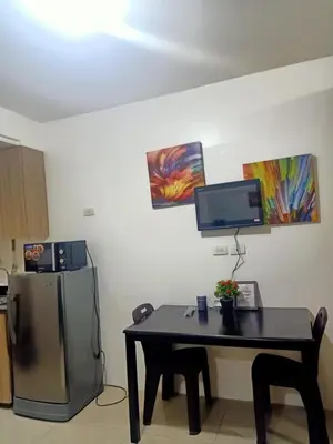 a kitchen with a table and a television on a wall at Staycation in Shore Residence's in Manila