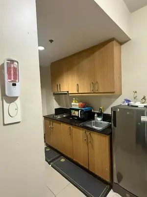 a kitchen with wooden cabinets and a stainless steel refrigerator at Sun&sky city escape in Manila