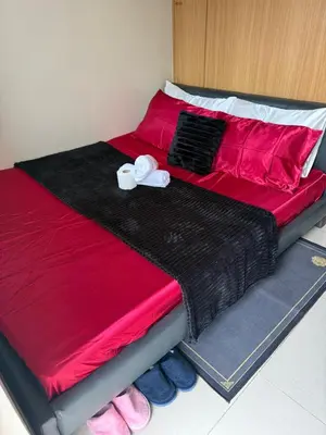 a bed with red and black sheets and shoes on it at Sun&sky city escape in Manila