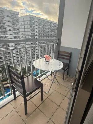 a table and chairs on a balcony with a view of buildings at Sun&sky city escape in Manila