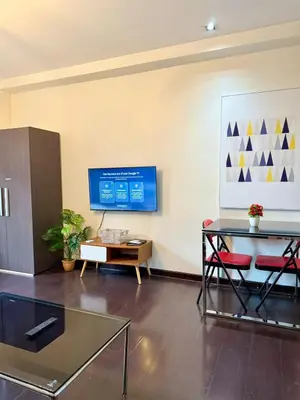 a living room with a glass table and a tv at Makati City Poblacion 1 bedroom with balcony in Manila