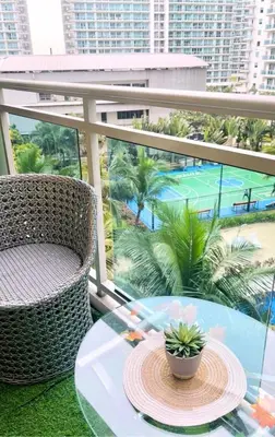 a glass table and chair on a balcony with a tennis court at 1BR 4Pax Condo Azure Beach Resort Pool View Fully Furnished with PS4 in Manila