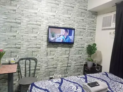 a television on a wall with a stone wall at Urban Deca Tower at Mandaluyong in Manila