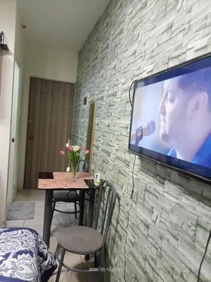 a television hanging on a brick wall with a table and chairs at Urban Deca Tower at Mandaluyong in Manila