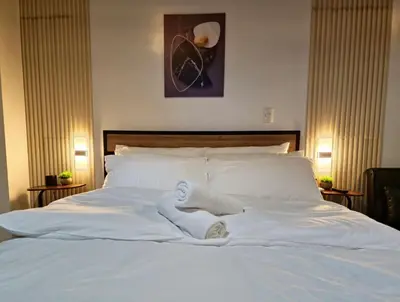 a white bed with two white towels on it at Luxe Spacious Cozy Venice BGC 65inTV Surround Sound in Manila