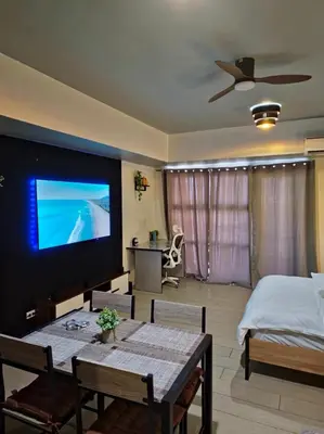 a living room with a bed and a large screen television at Luxe Spacious Cozy Venice BGC 65inTV Surround Sound in Manila