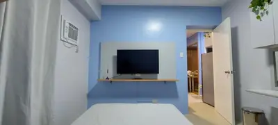 a blue room with a bed and a television at Avida Sucat Paranaque City in Manila