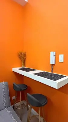 a counter with two stools and an orange wall at Direct Access to pool GK Suite in Manila