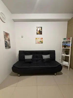 a black couch sitting in a white room at Luxe Condo at MOA in Manila