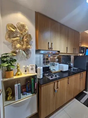 a kitchen with wooden cabinets and a counter top at Cozy 1BR Balcony Pool View with WiFi & Netflix near MOA and NAIA Airport in Manila
