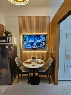 a kitchen with a table and chairs and a tv at Cozy 1BR Balcony Pool View with WiFi & Netflix near MOA and NAIA Airport in Manila