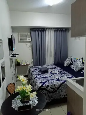 a bedroom with a bed and a table with flowers at Urban Deca Tower at Mandaluyong in Manila