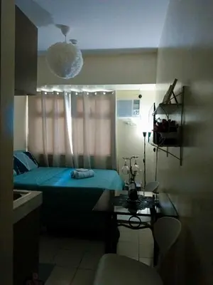 a small bedroom with a blue bed and a table at Urban Deca Tower at Mandaluyong in Manila