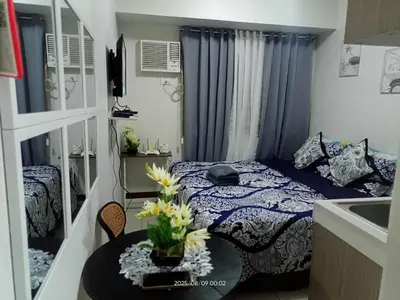 a bedroom with a bed and a table with flowers on it at Urban Deca Tower at Mandaluyong in Manila