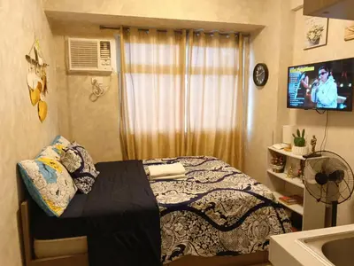 a small bedroom with a bed and a television at Urban Deca Tower at Mandaluyong in Manila