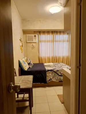 a small bedroom with a bed and a window at Urban Deca Tower at Mandaluyong in Manila