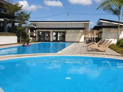 a large blue swimming pool in front of a house at Cozy 2BR Stay Near SM Dasma with Parking Space! in Palapala
