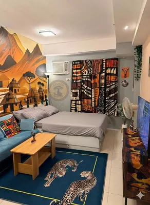 a room with two beds and a couch and a table at Cozy African Home in Parañaque in Manila