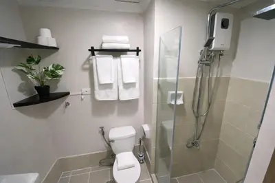 a bathroom with a toilet and a shower with towels at 2 BR Fully Furnished Condo in Parañaque with Pool and Parking - Bloom Unit 1134 in Manila