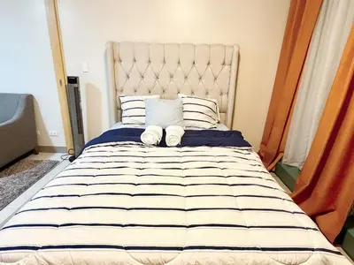 a bedroom with a large bed with striped sheets and pillows at BGC Luxe Condo I Facing Grand Hyatt & Uptown Mall in Manila