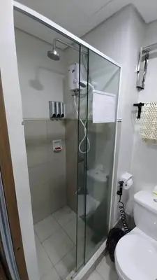 a glass shower in a bathroom with a toilet at MC Staycation at Spring Residences Near Airport in Manila