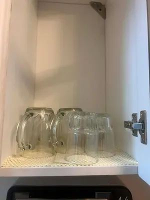 three wine glasses sitting on top of a shelf at MC Staycation at Spring Residences Near Airport in Manila