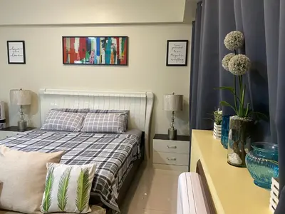 a bedroom with a bed and a table with two lamps at Theresa Place Like Home in Manila