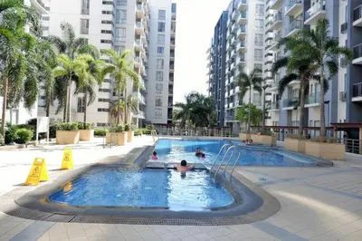 a pool with people in it with palm trees and buildings at Theresa Place Like Home in Manila