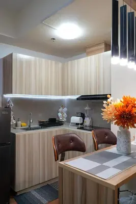 a kitchen with wooden cabinets and a table with chairs at Cozy Staycation in The Radiance Manila Bay in Manila
