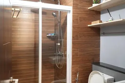 a shower in a bathroom with wooden walls at Cozy Staycation in The Radiance Manila Bay in Manila