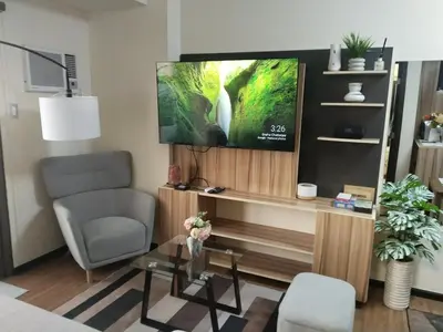 a living room with a tv and a chair and a table at Cozy Staycation in The Radiance Manila Bay in Manila