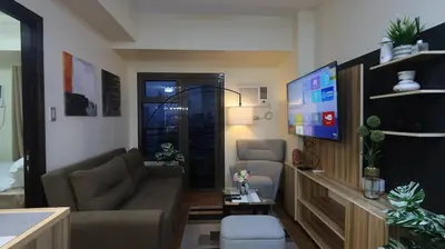 a living room with a couch and a flat screen tv at Cozy Staycation in The Radiance Manila Bay in Manila