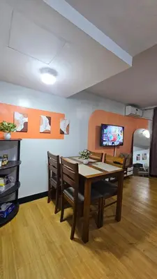 a dining room with a table and chairs and a tv at Bright & Airy Loft Cambridge Village Charm in Cainta