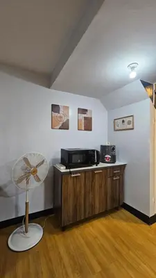 a room with a table with a fan and a microwave at Bright & Airy Loft Cambridge Village Charm in Cainta